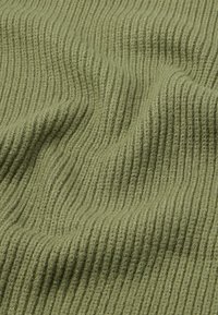 Tissu côtelé vert olive avec une texture douce, comportant des côtes verticales régulièrement espacées, créant un motif continu en forme de vague.