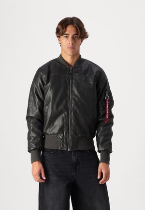 Black leather bomber jacket with ribbed cuffs and hem, featuring a front zipper and a side pocket with a red keychain accent.