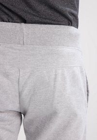 Gray sweatpants with a soft texture, ribbed elastic waistband, and side pockets. The fabric appears lightweight and casual.