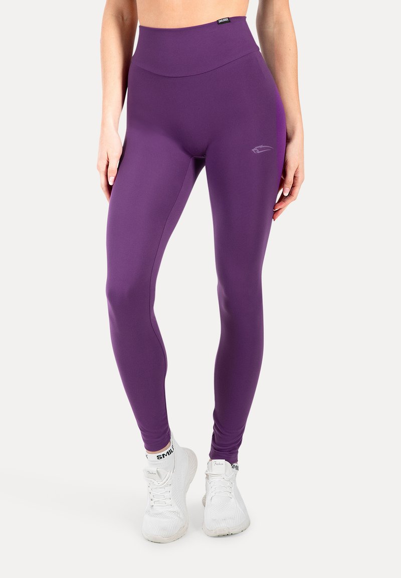 Leggings morados de cintura alta, elaborados con material elástico, que presentan una textura suave y un pequeño detalle de logo en el lateral.