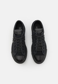 Černé tenisky Converse All Star s plátěným svrškem, gumovou špičkou, černými tkaničkami a logem na jazyku.