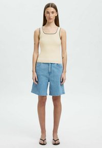 Beež ribaga särgitop musta äärega, koos helesiniste denim lühikeste pükstega, millel on vabalt langev lõige ja sirge lõige. Mustad plätud.
