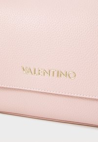 Rózsaszín bőr clutch táska, texturált felülettel és arany "Valentino" logóval. Az élek mentén varrási részlet található.