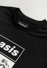 Tricou din bumbac negru cu guler rotund, având un grafic alb care spune "oasis" și un design ilustrat dedesubt. Textură moale.