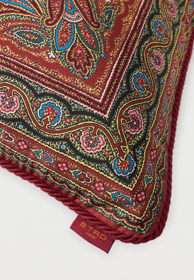 Coussin carré avec motif cachemire complexe rouge, vert, bleu et or, bordure torsadée bordeaux, avec une étiquette tissée "ETRO HOME".