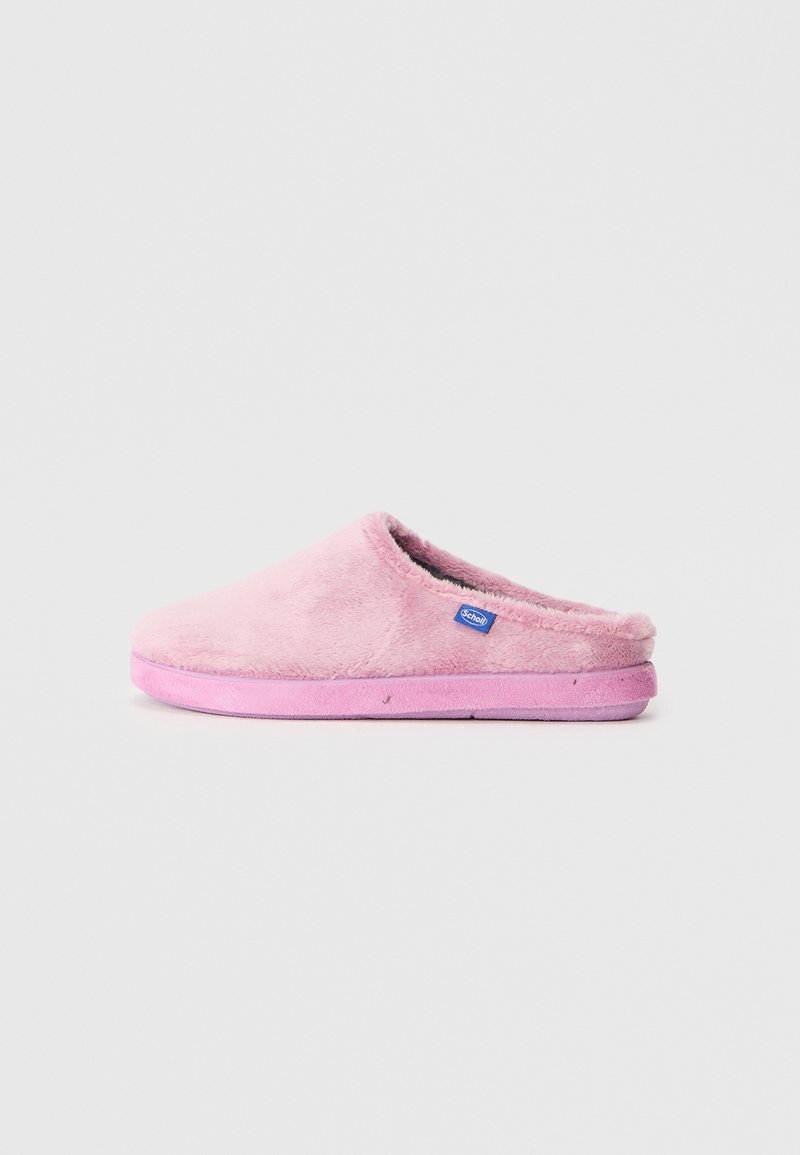 Zapatilla de casa rosa y suave con una textura blanda, forma redondeada y parte trasera abierta. Presenta una suela exterior de un rosa claro y una pequeña etiqueta de marca azul.