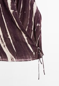Purple and cream wrap top with a textured fabric, featuring vertical stripes and a tie detail at the hem.