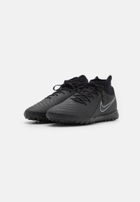 Zapatillas deportivas negras con parte superior texturizada, que cuentan con un cuello tipo calcetín, cordones y un prominente logo de swoosh blanco en el lado.