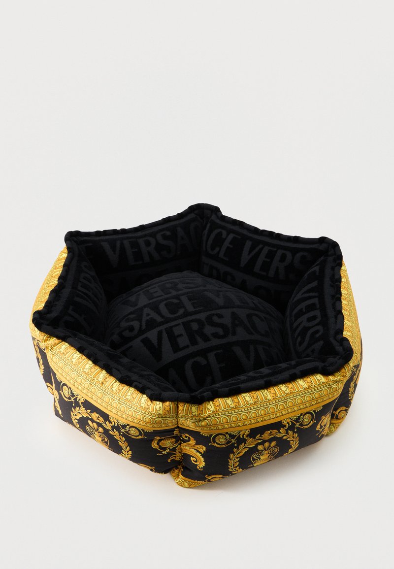 Εξαγωνικό κρεβάτι κατοικιδίου σε μαύρο και χρυσό χρώμα με περίτεχνο μπαρόκ σχέδιο και την επιγραφή «VERSACE» στο εσωτερικό μαξιλάρι και στις πλευρές.