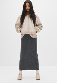 Beige zip-up bombali takki, vaaleanpunainen kerrospaita, tummanharmaa maksi-hame ja beige tennarit, joissa on tekstuuriset nauhat ja kermaiset sukat.