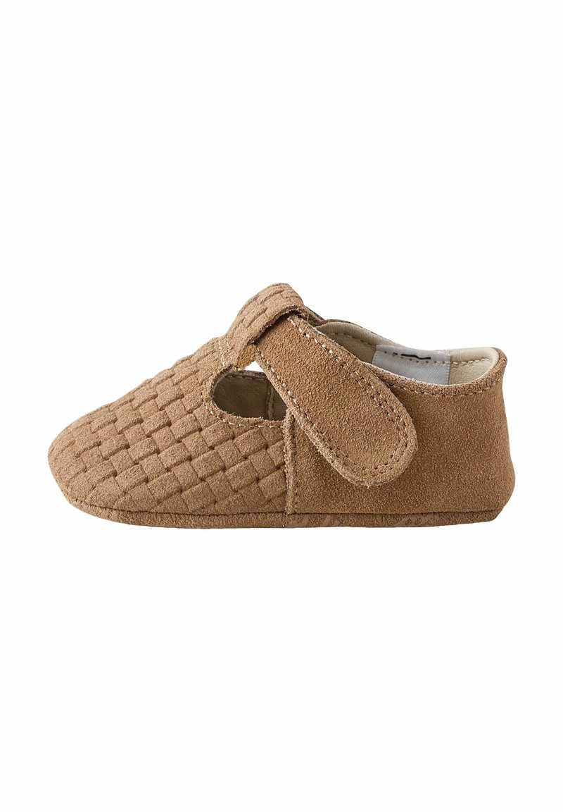 Chaussure en suède brun avec texture tissée, bout arrondi et une sangle auto-agrippante. Présente des côtés découpés, un doublure douce et une semelle plate.