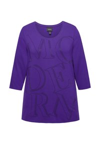 Violetti, pitkähihaista t-paitaa, jossa on pyöreä kaula-aukko. Esittelee suurta, mustaa rei'itettyä tekstiä, jossa lukee "MODERN." Pehmeä kangastuntuma.