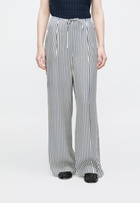 Hlače širokih nogavica s prugama u bijeloj i tamnoplavoj boji, s remenom za zatezanje u struku. Meki materijal s okomitim prugama za opušteni kroj.