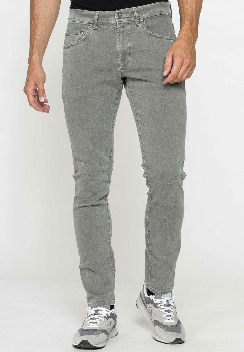 Jeans en denim gris clair avec une coupe slim, design à cinq poches et détails de couture discrets, associés à des chaussures de sport grises.