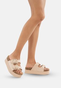 Plattformssandaler i mjuk beige mocka med dubbla spännen, texturerad korksula och en bred remdesign för komfort.