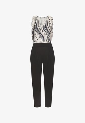 Mouwloze V-hals jumpsuit met zwarte taps toelopende broek en een wit topje met zwarte abstracte penseelstreekpatronen.