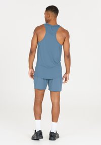 Blå atletisk tanktop og shorts lavet af letvægtsmateriale. Har racerback-design, flade sømme og minimalistisk stil.