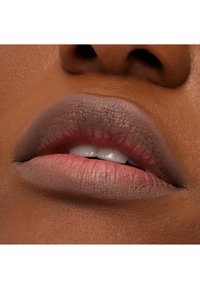 Matte huuliväri neutraaleissa ruskeissa sävyissä sileillä huulilla, joissa on hienovarainen väriharjanne, tuoden esiin luonnollisen koostumuksen ja siistin lopputuloksen.