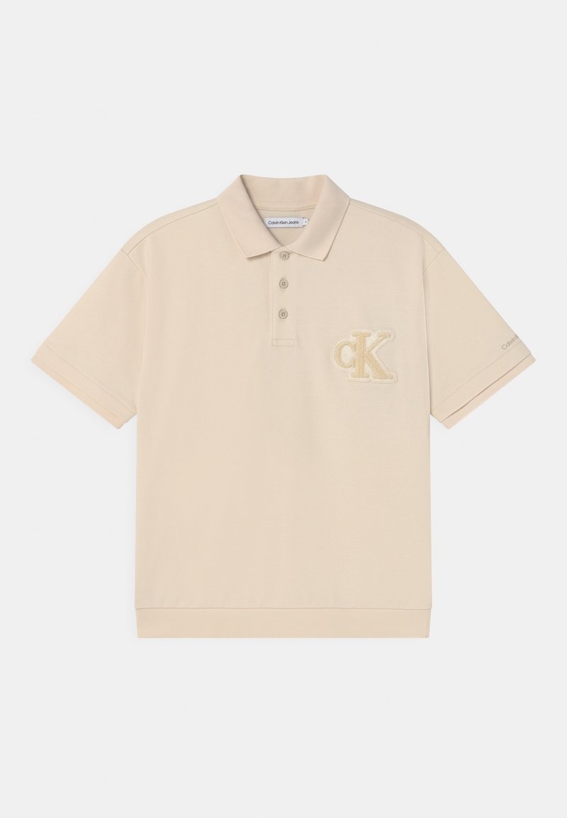 Beżowa koszulka polo z bawełny, z trzema guzikami oraz haftowanym logo "CK" na lewej piersi. Miękka faktura.