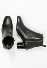 Bottines en cuir noir avec fermeture éclair, panneaux latéraux en élastique texturé et talon bloc glossy. Surface lisse, design à bout pointu.