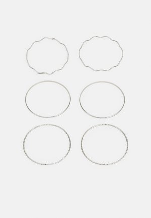 Set di quattro orecchini a cerchio in tonalità argento: due con texture ondulata, due lisci con spessori variabili, uno con un delicato motivo inciso.