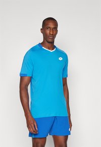 Blue athletic shirt with short sleeves, a white V-neck, and logo detail. Paired with blue shorts, both made of lightweight fabric.