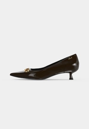 Chaussure femme en cuir verni marron foncé à bout pointu et talon bas, avec un petit détail de boucle dorée près du bout et une signature près du talon.