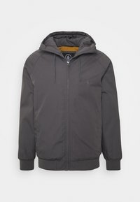 Chaqueta con capucha de color gris oscuro, con cierre frontal, cordones, puños elásticos y un pequeño logo en el lado izquierdo del pecho.