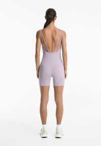 Svijetloplavi bodysuit s dubokim leđima i ukriženim trakama. Ima prilagođeni dizajn i kratke noge, izrađen od rastezljivog materijala.