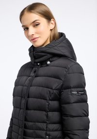Zwarte puffjas met capuchon, met een gevoerde textuur, glanzende knopen en logo-opdruk op de mouw. Slim fit, lichtgewicht ontwerp.