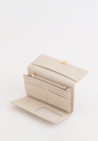 Beżowy skórzany portfel z złotym zapięciem, wieloma przegródkami na karty, przegrodą na zamek oraz przezroczystym okienkiem na identyfikator. Gładka faktura, prostokątny kształt.