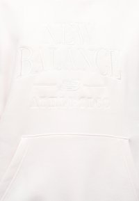 Λευκό φούτερ με ανάγλυφο κείμενο "New Balance Athletics" και λογότυπο πάνω από την τσέπη τύπου πουγκί στο μπροστινό μέρος.