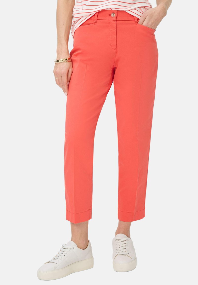 Pantaloni cropped in cotone misto corallo con taglio dritto, dotati di tasche laterali e chiusura con bottone, abbinati a sneaker bianche.