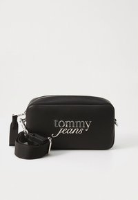Schwarze Umhängetasche aus synthetischem Material mit silbernem "tommy jeans"-Logo. Verfügt über einen Reißverschluss und einen abnehmbaren Riemen für Vielseitigkeit.