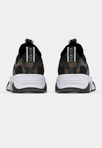 Μαύρα αθλητικά παπούτσια με υφή επάνω μέρος, λευκές σόλες και επαναλαμβανόμενο μοτίβο λογότυπου. Διαθέτουν λουράκια για εύκολη χρήση.