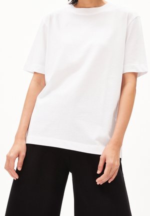 Biały bawełniany t-shirt z okrągłym dekoltem, krótkimi rękawami i luźnym krojem. Gładka tekstura z prostym, równym dołem w pasie.