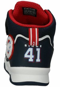 Marineblauer Sneaker mit roten Akzenten, weichen Details und einem Klettverschlussband. Mit einer weißen Sohle und der Nummer "41" auf der Rückseite gestickt.