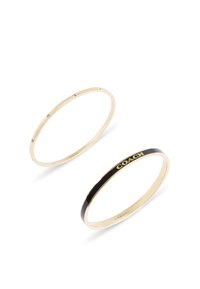 Två armband: ett i guldfärgad ton med små klara kristaller, det andra i guldfärgad ton med en svart rand och ingraverad "COACH." Båda är släta och cirkulära.