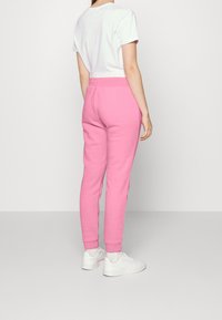 Rosa joggerbyxor av mjuk bomullsblandning, med elastisk midja och ribbade muddar. Kombineras med en enkel vit t-shirt och vita sneakers.