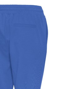 Modré sportovní kalhoty s elastickým pasem, hladkou texturou, boční kapsou a volným střihem. Tkanina působí lehce a prodyšně.