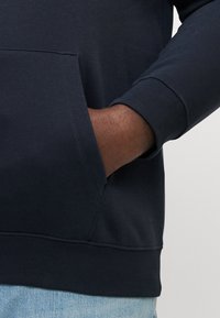 Navyblauwe sweatshirt met een kangoeroezak, ribgebreide manchetten en een zachte textuur. Minimalistisch ontwerp, getailleerde stijl en gemaakt van katoen.