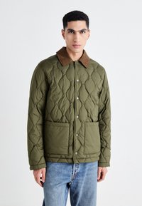Quilted olive green jacket with a brown corduroy collar, snap buttons, and two front pockets, featuring a textured, diamond-shaped pattern.