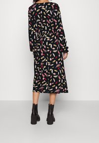 Černé šaty s barevnými vzory listů v růžové, žluté a bílé. Dlouhé rukávy, délka do poloviny lýtek, doplněné černými kotníkovými botami.