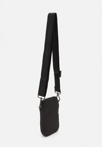 Borsa a tracolla nera con forma rettangolare, realizzata in tessuto testurizzato, dotata di una tracolla con logo e clip in metallo per il fissaggio.