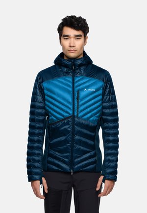 Veste isolée bleue avec capuche, dotée de matelassage en chevrons, d'une fermeture éclair à l'avant et d'un design à panneaux contrastants. Le matériau semble léger et lisse.