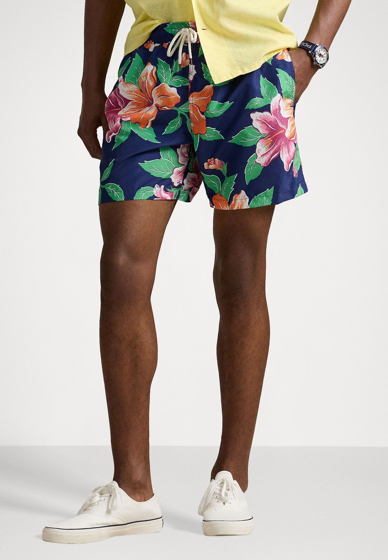 Floral swim shorts in navy featuring large orange and pink blossoms with green leaves; elastic waistband with drawstring, and side pockets.
