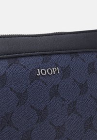 Trousse en tissu à motif marine avec une surface texturée, dotée d'une garniture en cuir foncé et d'un accent en logo argenté "JOOP!".