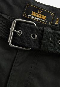 Czarne spodnie z teksturowanym wplecionym paskiem, srebrną klamrą metalową i metką z napisem "NEXT Durable Goods" w rozmiarze 32R.
