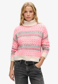 Pull en rose et gris à motifs avec un col montant, fabriqué en matériau doux, présentant des formes de losanges et un ourlet et des poignets côtelés.