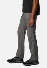 Gray cargo pants made of lightweight fabric, featuring side pockets, a relaxed fit, and reinforced stitching at seams. Paired with black hiking shoes.